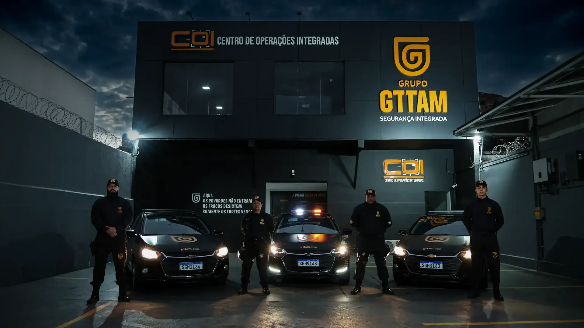 Fachada do COI da GTTAM à noite, com agentes e viaturas posicionados na frente da base